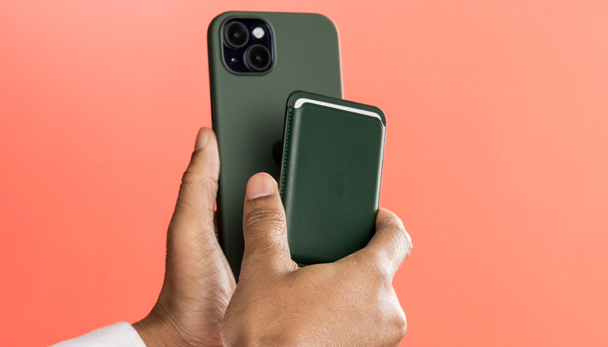 Twee handen houden een groene leren MagSafe kaarthouder bij een groen siliconen hoesje met iPhone.