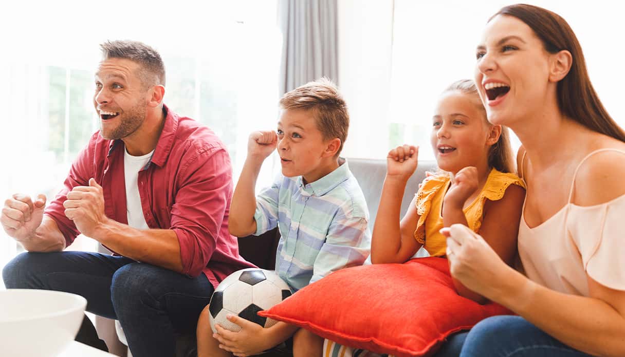 Gezin zit op de bank te kijken naar de wedstrijd van EK voetbal 2024, ze juichen voor het Nederlands elftal.