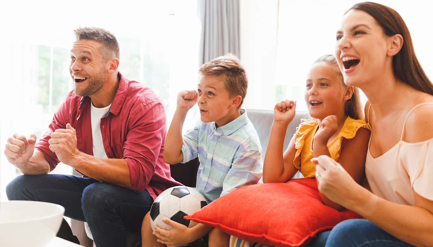 Gezin zit op de bank te kijken naar de wedstrijd van EK voetbal 2024, ze juichen voor het Nederlands elftal.