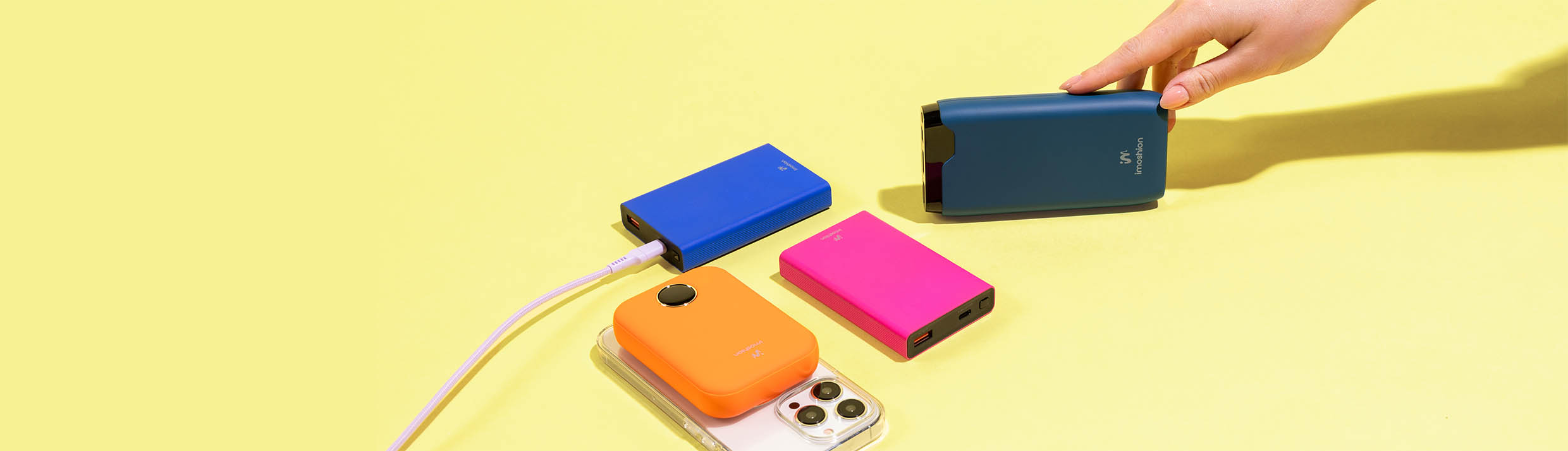 verschillende powerbanks in vrolijke kleuren op een gele achtergrond.