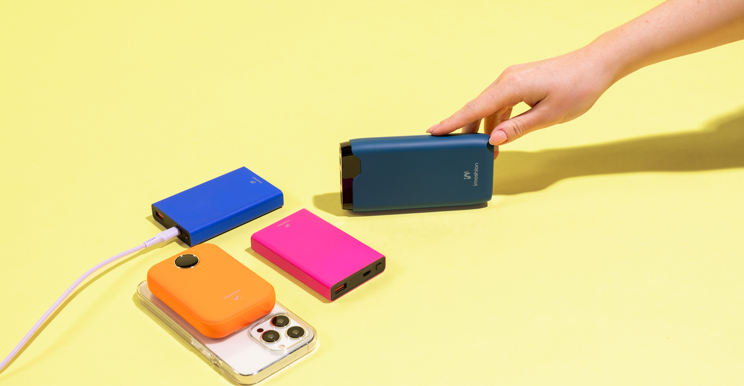 4 verschillende kleurrijke powerbanks, waarvan 1 MagSafe powerbank die aan een iPhone gekoppeld is, met een reikende hand naar een van de powerbanks.