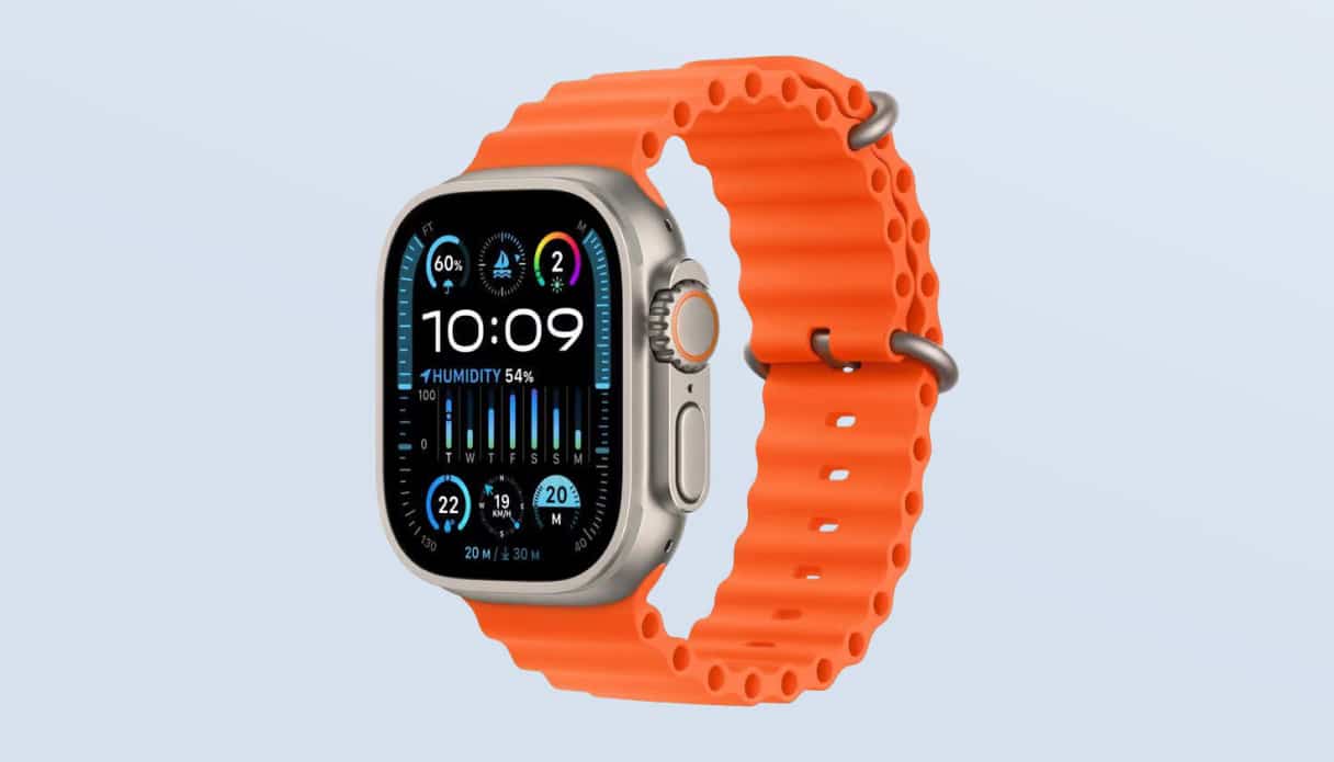 Je ziet een Apple Watch Ultra met titaniumkleurige behuizing en een oranje Ocean bandje op een lichtblauwe achtergrond.