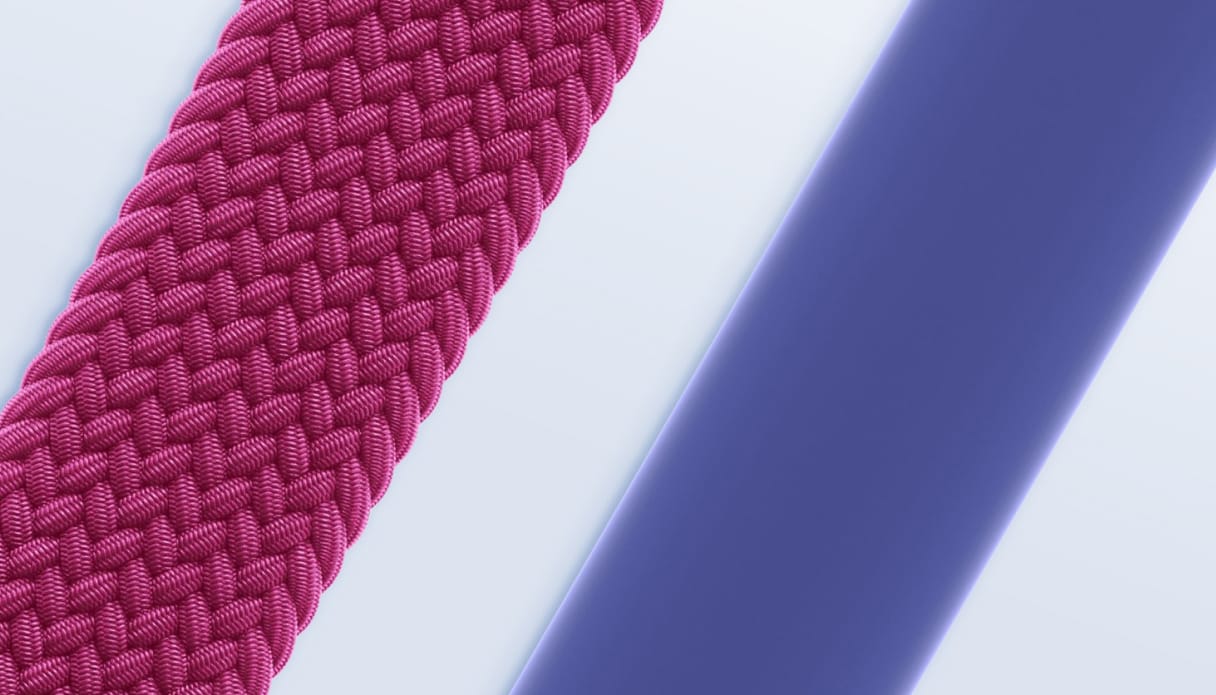 Detailshot van twee Apple solobandjes op een lichtblauwe achtergrond, links een wijnrood gevlochten solobandje en rechts een paars siliconen solobandje.