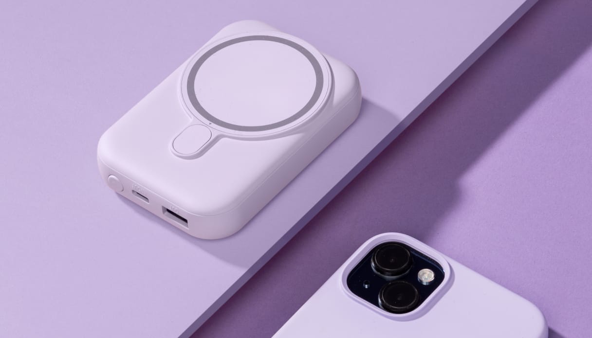 Een iPhone met een lila hoesje met daarnaast een lila powerbank.