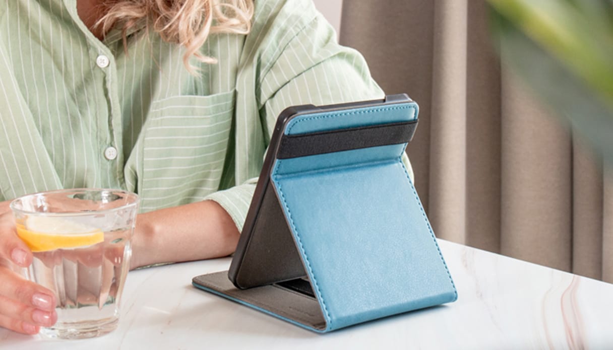 Foto van een persoon met een glas water en een e-reader in een flipcover.