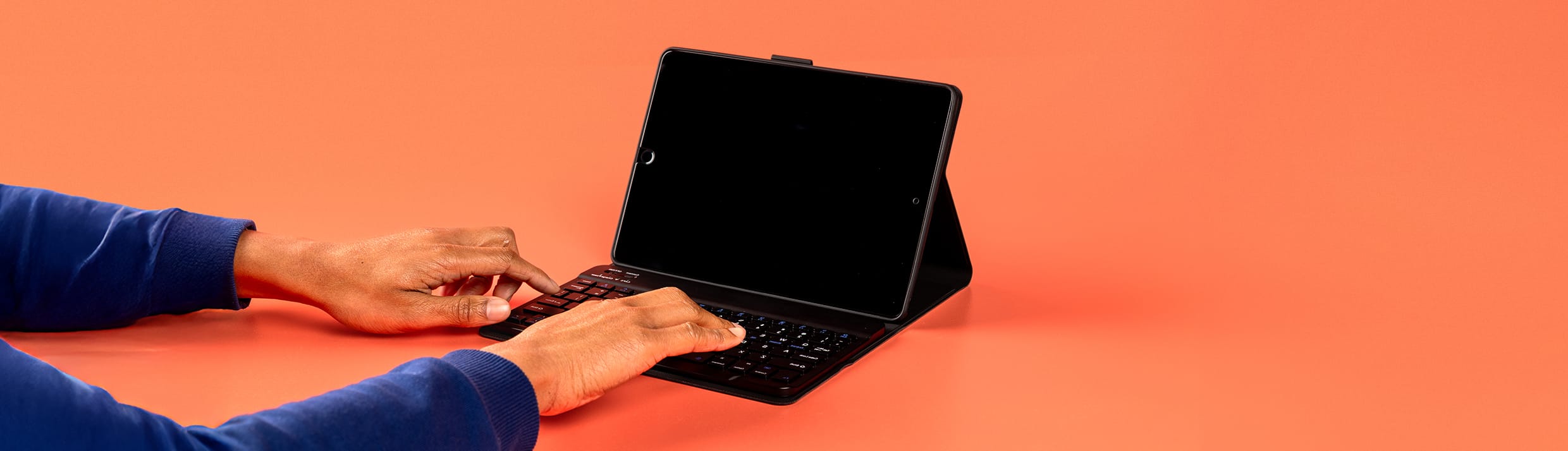 Tablethoes met toetsenbord op een oranje backdrop.