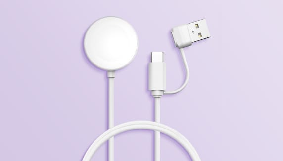 Op een paarse achtergrond ligt een witte Apple Watch oplaadkabel met USB-C aansluiting en een afkoppelbare USB-A adapter.