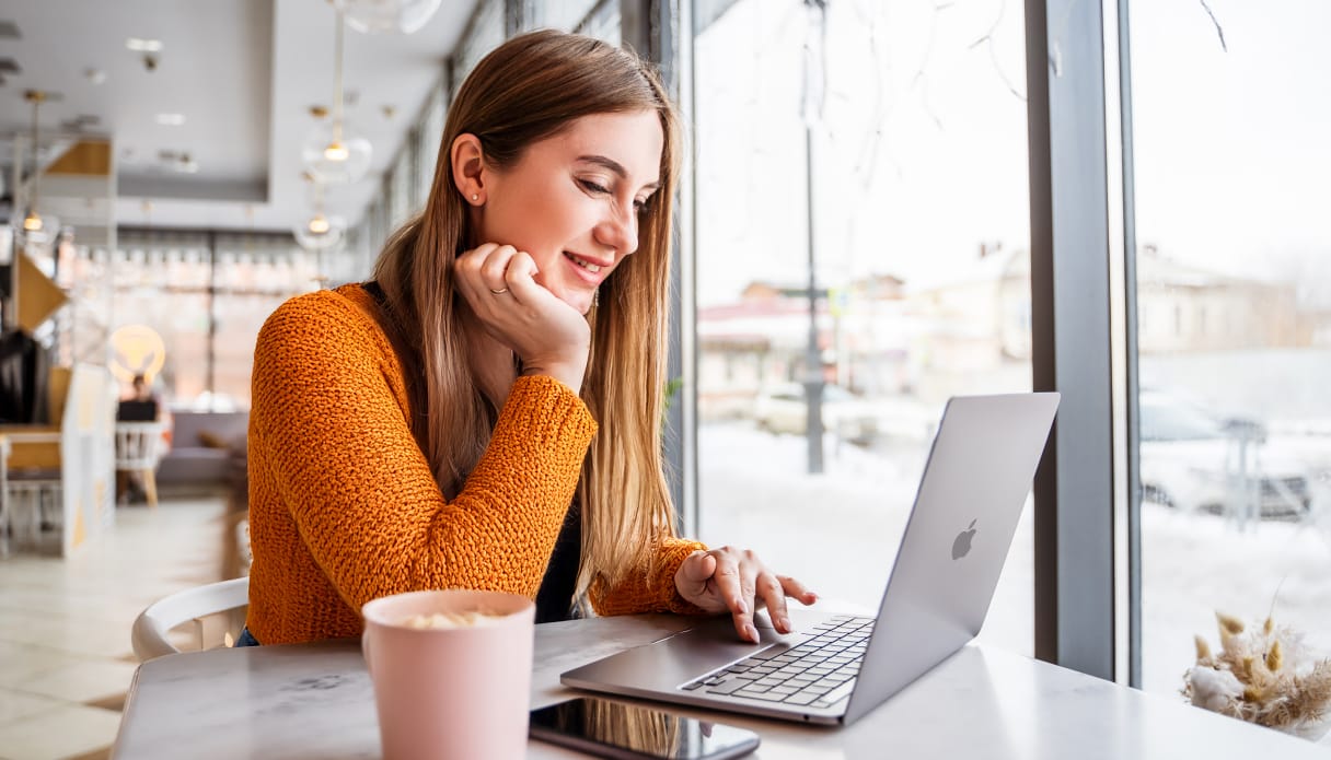 Een vrouw werkt op haar MacBook in een café.