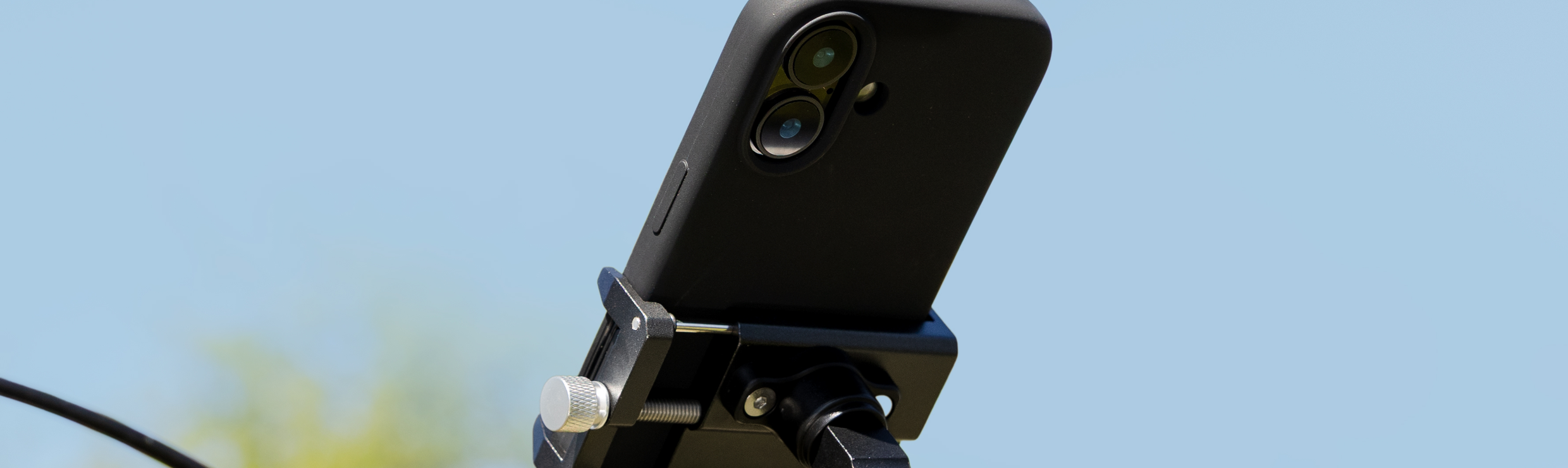 Een iPhone in een telefoonhouder op een fietsstuur, met een blauwe lucht als achtergrond.