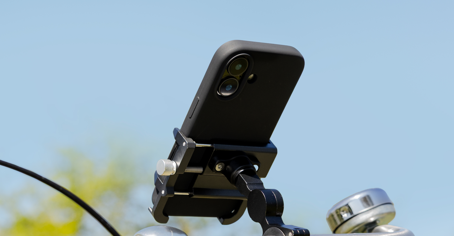 Een iPhone in een telefoonhouder op een fietsstuur, met een blauwe lucht als achtergrond.