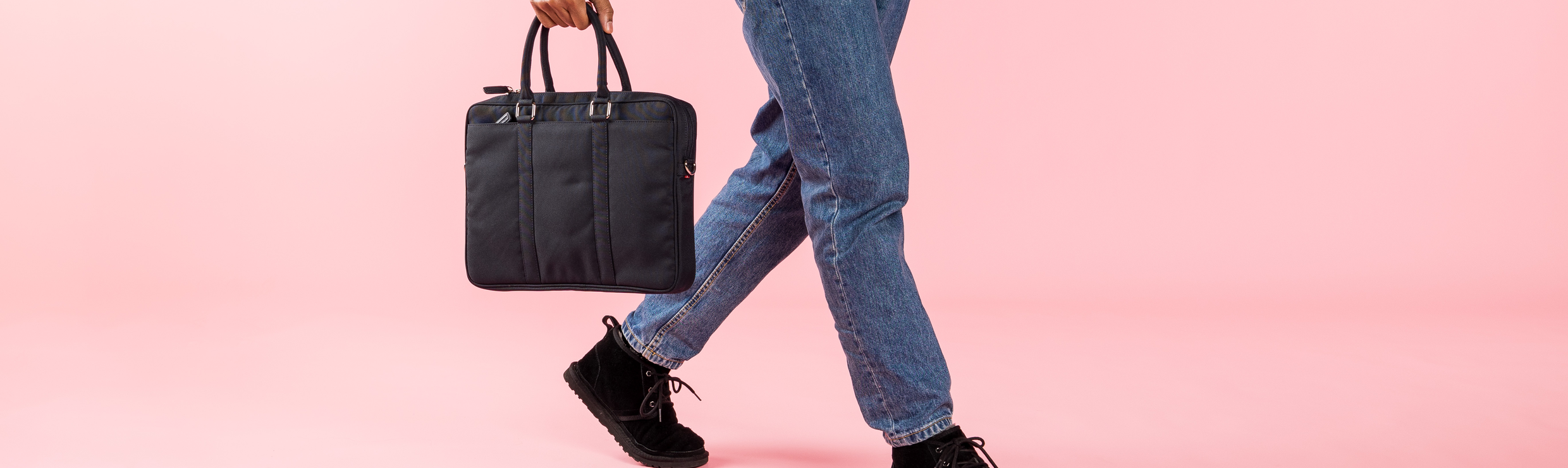 Een man loopt met een laptoptas in zijn hand.