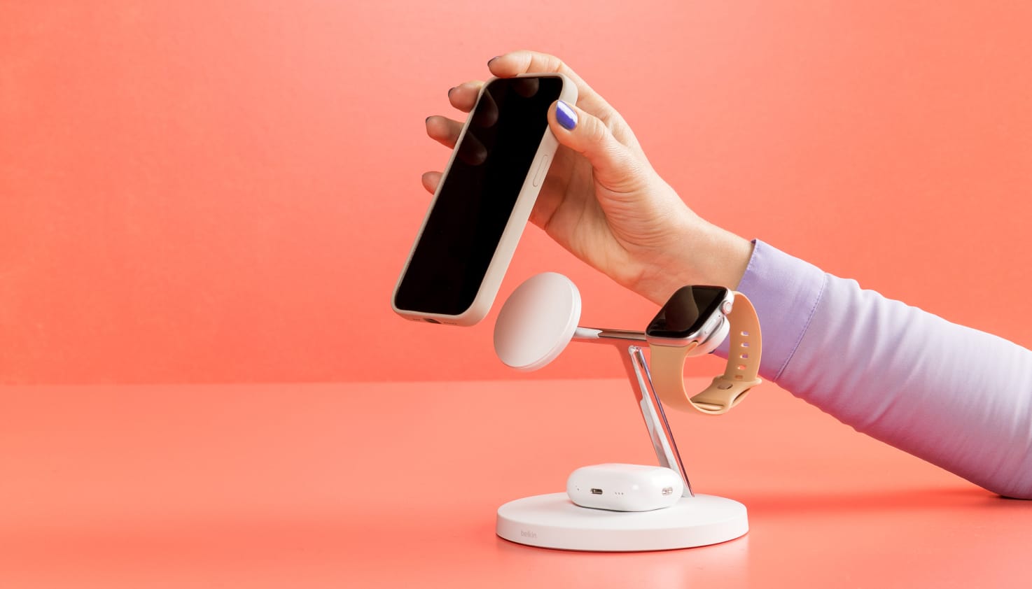 Een draadloze oplaad standaard met een telefoon, smartwatch en oordopjes.