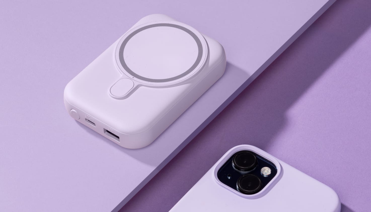 Een iPhone met een lila hoesje met daarnaast een lila powerbank.