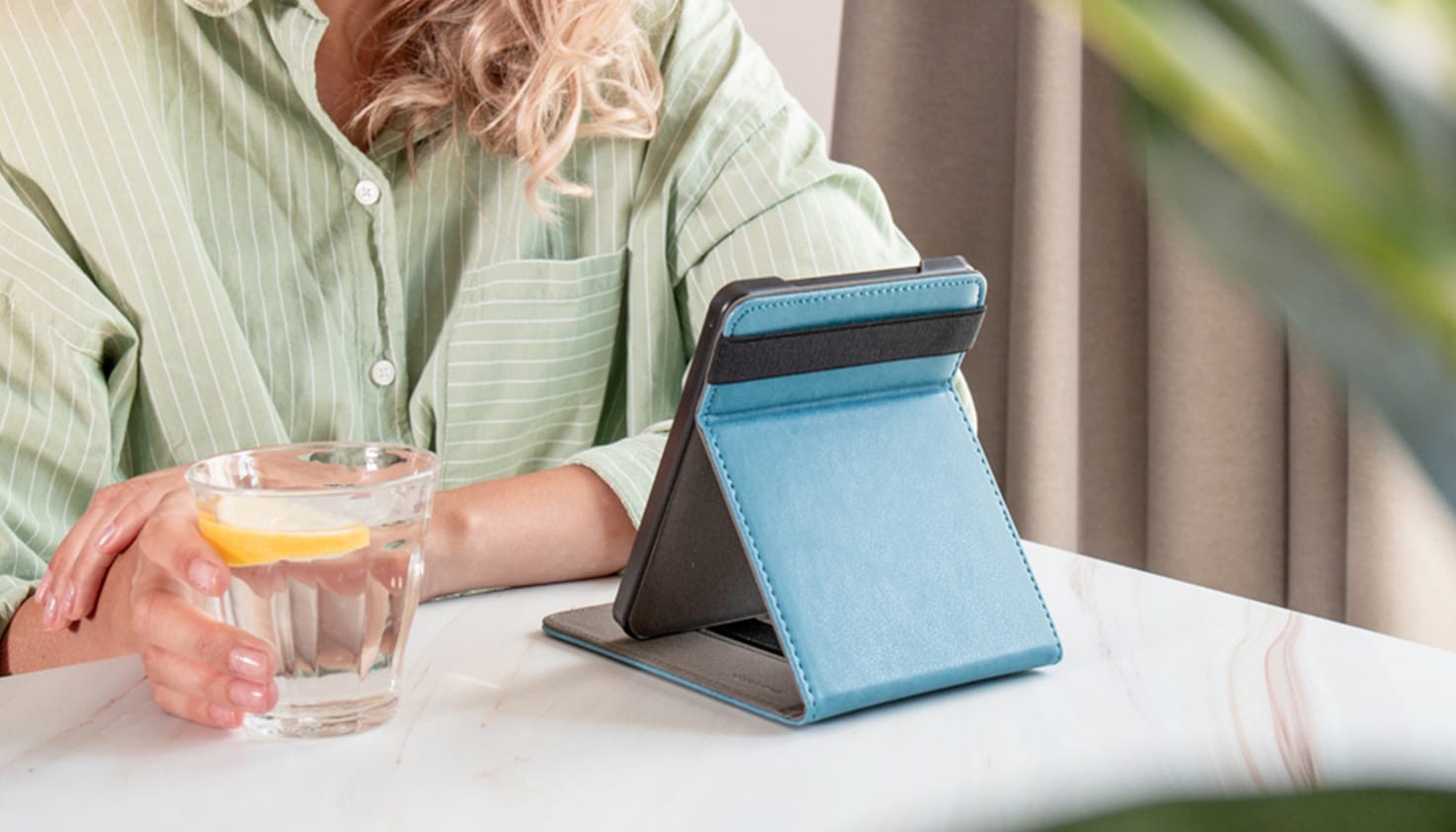 Foto van een persoon met een glas water en een e-reader in een flipcover.