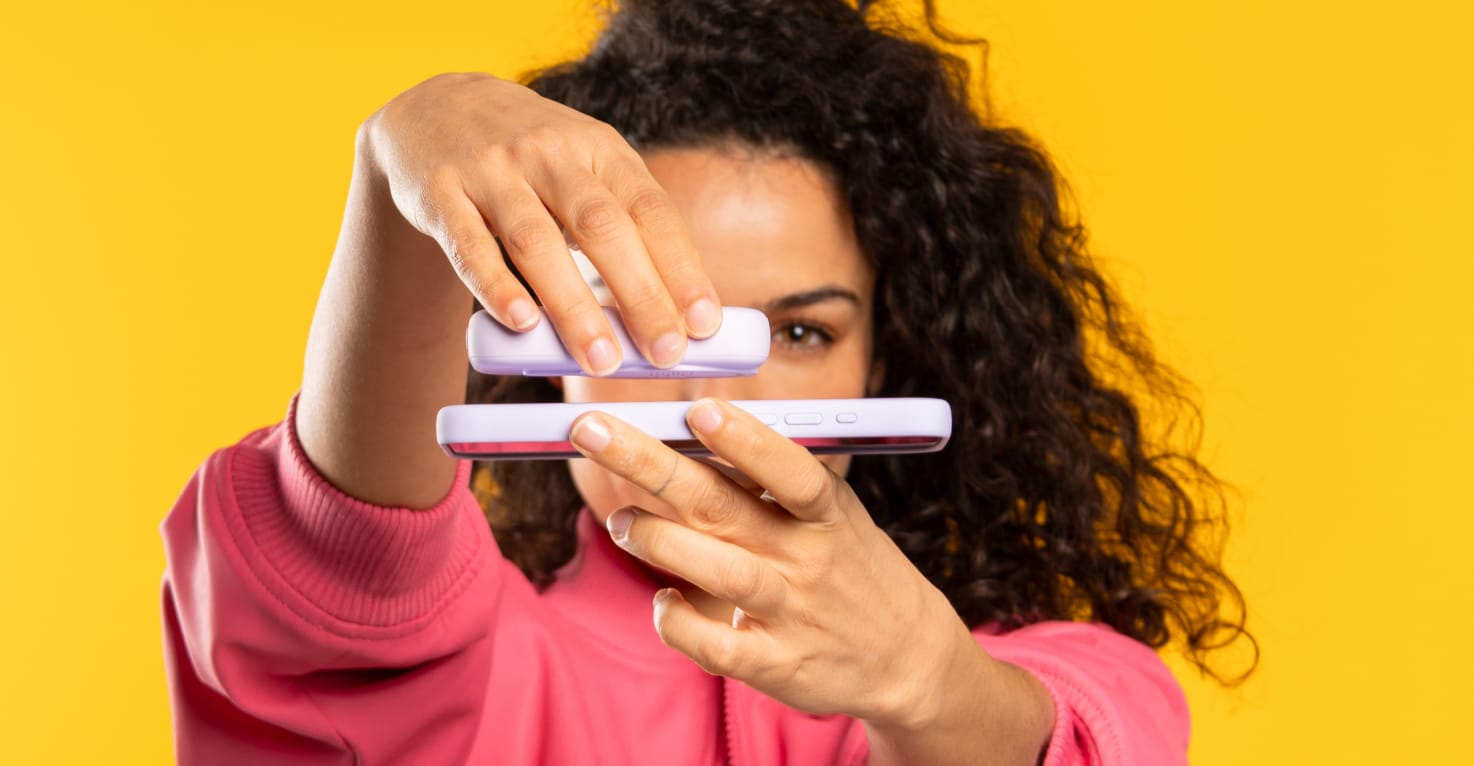 Een vrouw klikt een powerbank magnetisch aan haar telefoon met MagSafe.