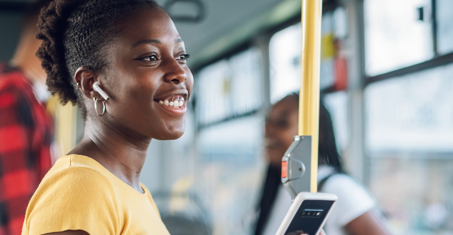 Een vrouw in de bus met draadloze oordopjes.