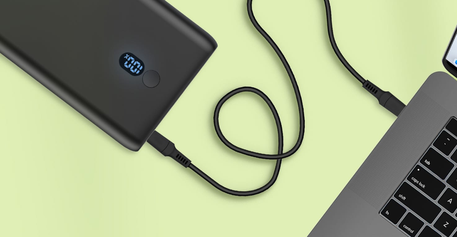 Een zwarte powerbank laadt een MacBook op.