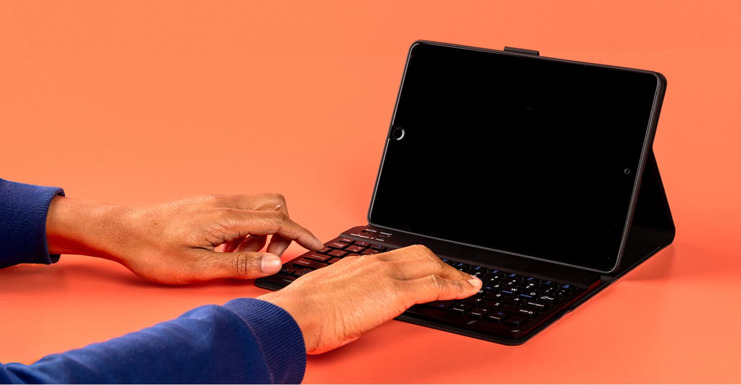 Tablethoes met toetsenbord op een oranje backdrop.