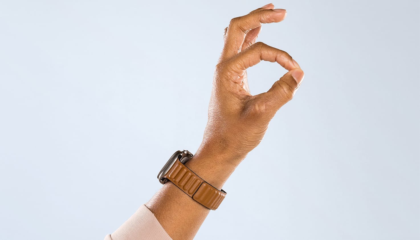 Foto van deel van een arm met hand. De persoon heeft een smartwatch om en beeld het universele 'okay' teken uit.