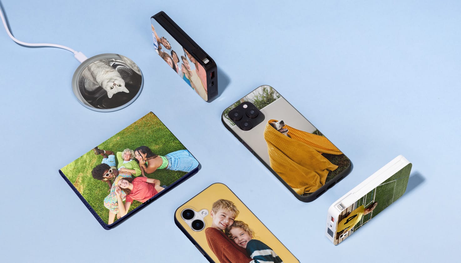 Je ziet verschillende producten die bedrukt zijn met een eigen ontwerp, zoals telefoonhoesjes, powerbanks, een draadloze oplader een paspoorthoes.