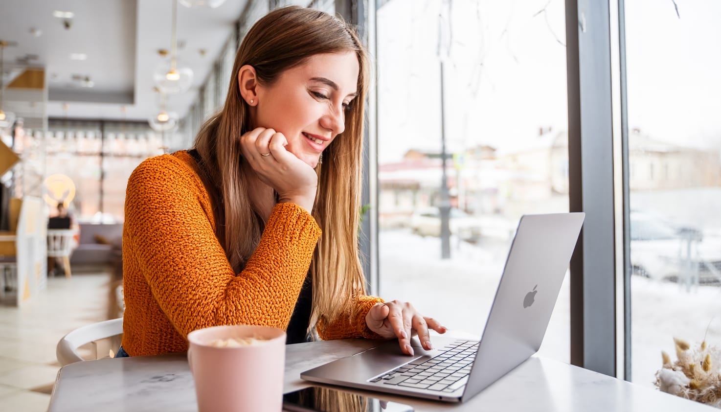 Een vrouw werkt op haar MacBook in een café.