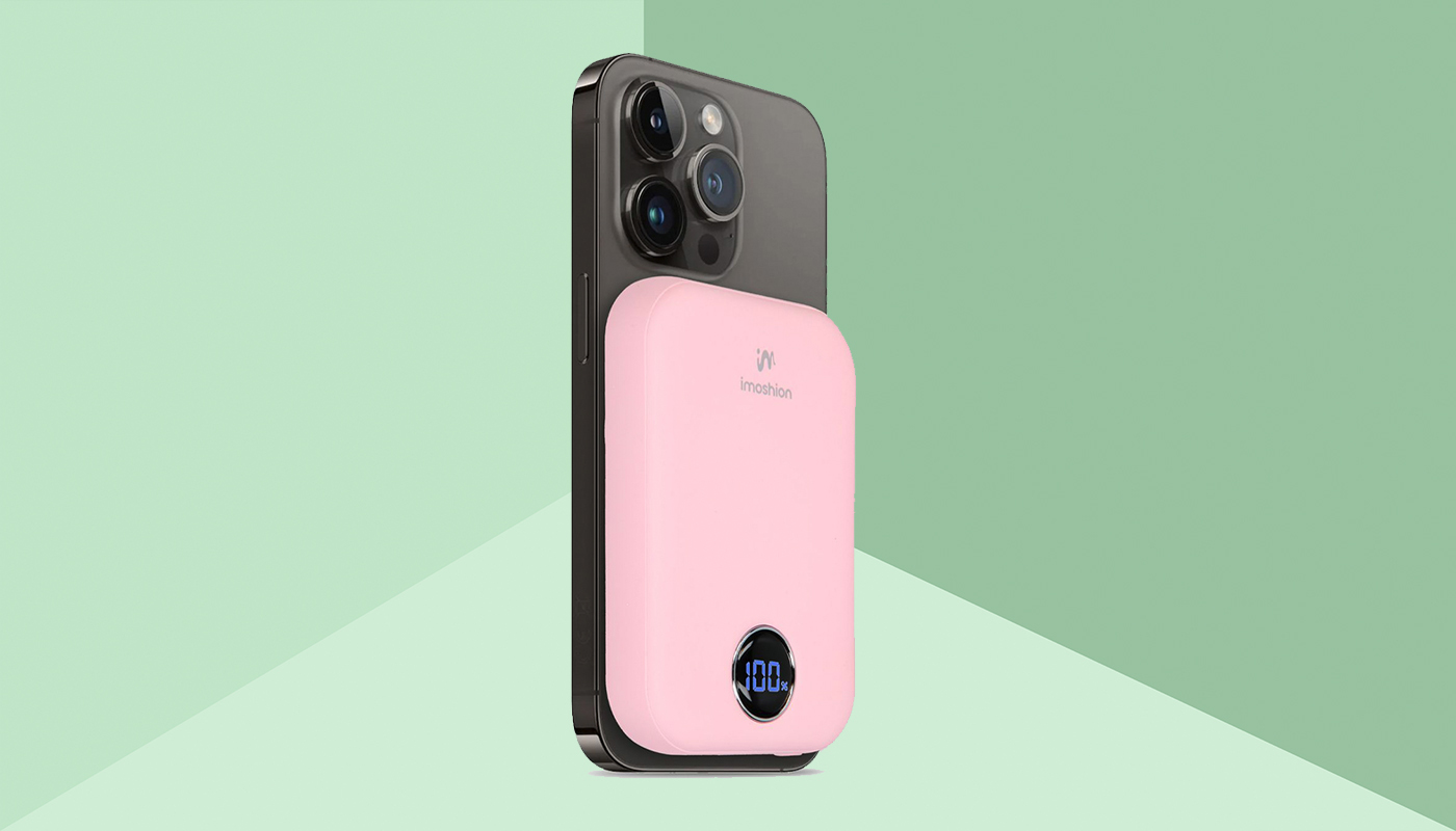 Een roze MagSafe powerbank op een iPhone 15 Pro, de achtergrond is groen.