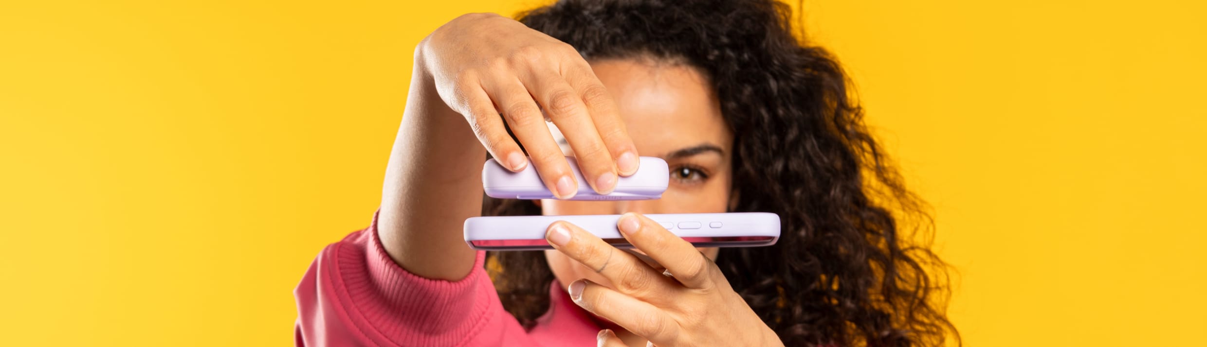 Een vrouw klikt een powerbank magnetisch aan haar telefoon met MagSafe.